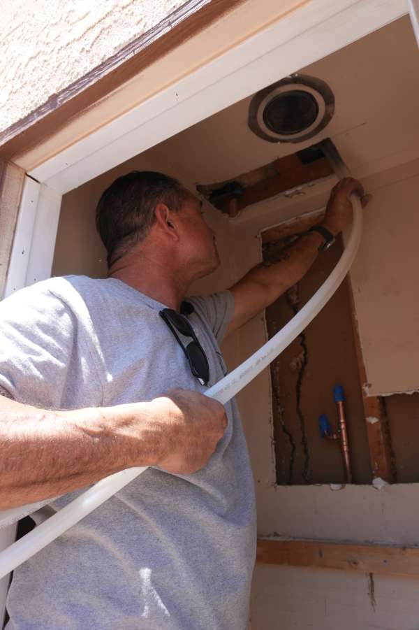 Royalty Plumbing plumber connecting supply lines and drain under Las Vegas kitchen sink